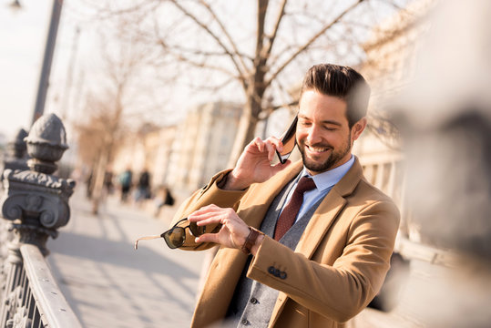 An Elegant Man Walking And Talking On His Phone