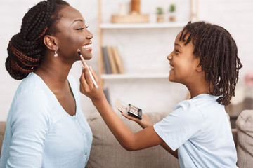 African american daughter doing makeup for mother