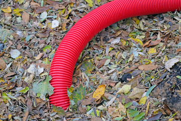 Red flexible double-walled pipe for cable ducts. A corrugated plastic pipe is buried in the ground...