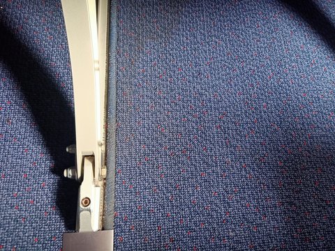 the metal seat leg attach on blue velvet carpet by 2 bolts  in passenger room of the plane
