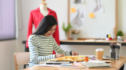 Tailor asian woman working on designer studio workspace.