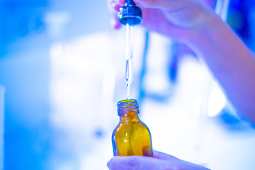 hands active substance is added dropwise with pipette and glass flask in laboratory