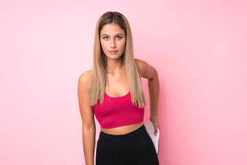 Young sport blonde woman stretching over isolated pink background