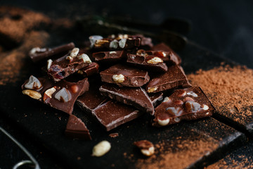 Slices of milk chocolate with nuts and dried fruits on a wooden board
