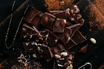 Slices of milk chocolate with nuts and dried fruits on a wooden board