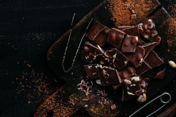 Slices of milk chocolate with nuts and dried fruits on a wooden board