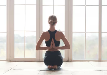 Foto op Plexiglas Back view of girl meditating in reverse prayer pose © Prostock-studio