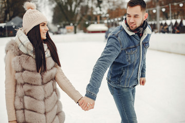 Beautiful couple have fun in a ice arena. Elegant girl in a fur coat. Man in a jeans jacket