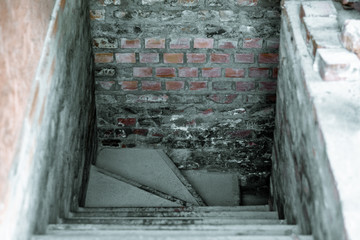Entrance to a dark basement with brick walls. Descent to the old basement