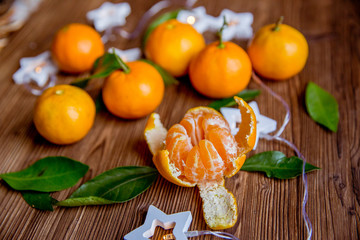 Christmas and new year decor. Christmas card. Tangerines, candle, lights, cones on a wooden background