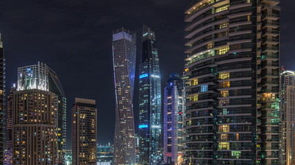 View of various skyscrapers and towers in Dubai Marina from above aerial night timelapse