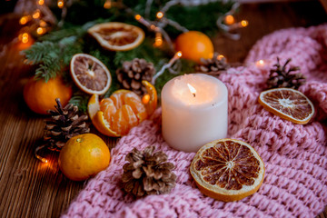 Obraz na płótnie Canvas Christmas and new year decor. Christmas card. Tangerines, candle, lights, cones on a wooden background
