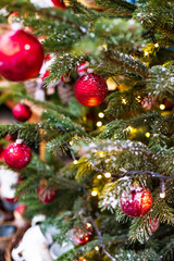 Outdoor decorated Christmas tree with light garland and red balls, selective focus