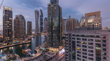 Fototapeta premium Aerial view of Dubai Marina residential and office skyscrapers with waterfront day to night timelapse