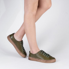 classic low top lace up womens leather sneakers. Photo on legs of a model on a white background