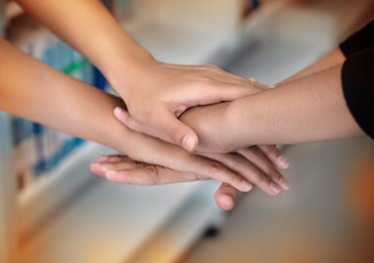 In selective focus of human hands stacked togethersign and symbol of togetherness,the collaboration,unity,blurry light around