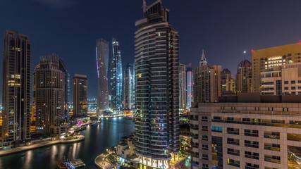 Fototapeta na wymiar Aerial view of Dubai Marina residential and office skyscrapers with waterfront night timelapse
