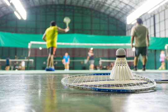 shuttlecock resting on a badminton racket with badminton player are competiting