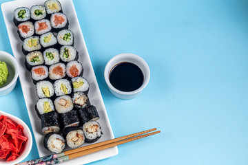 Sushi with fish, with cucumber, with eel, with avocado. Wrapped in Nori Seaweed. Food for vegetarians. Soy sauce, ginger, wasabi in white bowls. Copy space.