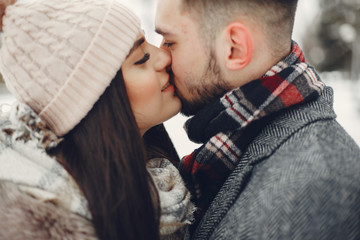 Couple in a winter park. Beautiful girl in a fur coat. Man in a jeans jacket.