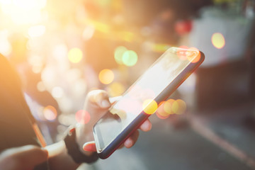 Close up woman hand hold using smart phone on outdoor park street background.