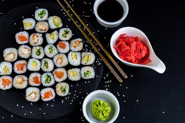 Sushi with fish, with cucumber, with eel, with avocado. Wrapped in Nori Seaweed. Food for vegetarians. Soy sauce, ginger, wasabi in white bowls. Copy space.