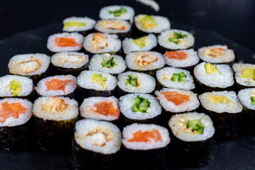 Sushi with fish, with cucumber, with eel, with avocado. Wrapped in Nori Seaweed. Food for vegetarians. Soy sauce, ginger, wasabi in white bowls. Copy space.
