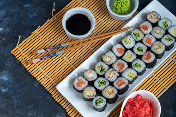 Sushi with fish, with cucumber, with eel, with avocado. Wrapped in Nori Seaweed. Food for vegetarians. Soy sauce, ginger, wasabi in white bowls. Copy space.