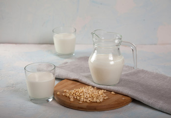Vegetarian pine nut milk in glass cups and jug, on white background. Copy spais. horizontal