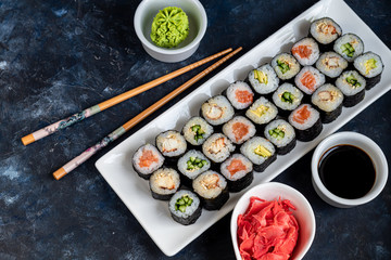 Sushi with fish, with cucumber, with eel, with avocado. Wrapped in Nori Seaweed. Food for vegetarians. Soy sauce, ginger, wasabi in white bowls. Copy space.