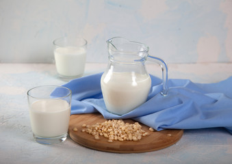 Vegetarian pine nut milk in glass cups and jug, on white background. horizontal