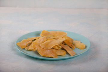 Natural mango chips on a blue plate on a light background. Horizontally