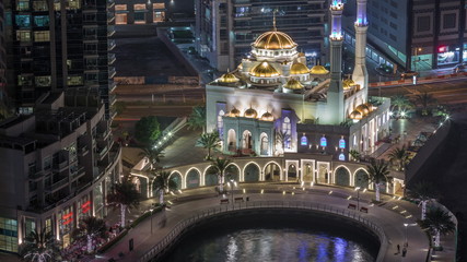 Modern residential architecture of Dubai Marina and Mohammed Bin Ahmed Almulla Mosque aerial night timelapse