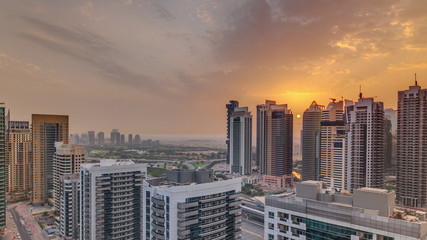 Fototapeta premium Sunrise view of various skyscrapers and towers in Dubai Marina from above aerial timelapse
