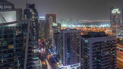 Fototapeta premium View of various skyscrapers and towers in Dubai Marina from above aerial night timelapse