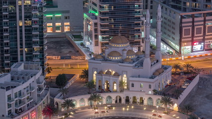 Modern residential architecture of Dubai Marina and Mohammed Bin Ahmed Almulla Mosque aerial night to day timelapse
