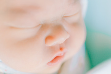 tender lips and nose of a newborn baby asleep on a diaper