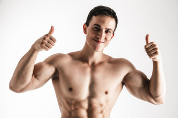 Fototapeta premium Portrait of handsome young man showing thumbs up over white background. Perfect hair & skin. Close up. Studio shot