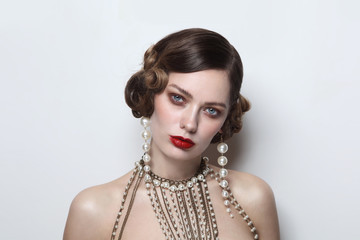 Vintage style portrait of young beautiful woman with fancy pearl earrings and necklace