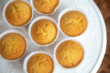 vanilla cupcakes on white plate  on wooden table