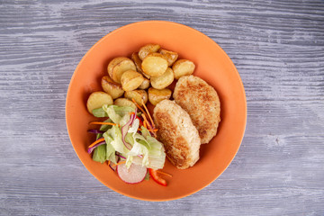 Meat cutlets with baked potatoes, served with fresh vegetables