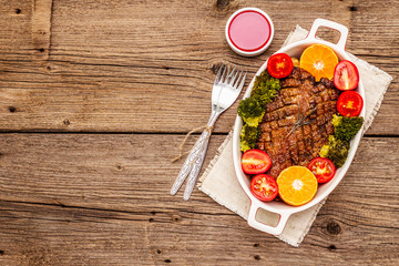 Baked duck breast on the bone with vegetables and sauce. Traditional healthy food concept. Vintage wooden boards background