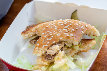 Eating fast food, bitten hamburger burger in a restaurant. Unhealthy food.