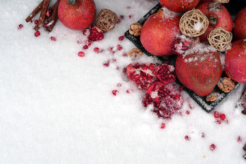 Fresh red  pomegranate with cinnamon, nuts on  snow