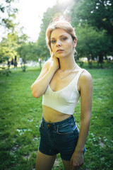 Portrait of a young blonde woman in a park at sunset in summer