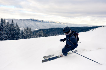 Skier inclining turning on snow-capped mountain peak. Backcountry skier doing professional skiing...