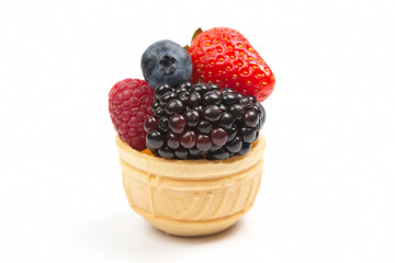 blueberries, raspberries, strawberries and blackberries in a waffle basket on a white background