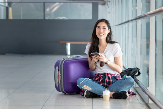 Beautiful Asian Girl solo traveller holding passport and waiting for flight travel at international airport terminal. Charming Beautiful woman go to foreign country for Holiday. Flight schedule.