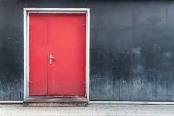 Red door on a black wall background. The modern facade of the building. Urban concept.