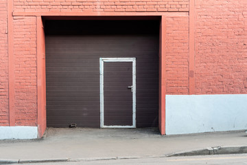 Obraz na płótnie Canvas Brick facade with a modern brown gate.
